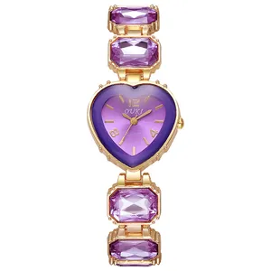 Macro di un orologio al quarzo dorato con quadrante viola a cuore e cristalli viola