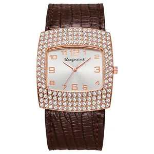 Detail view of square rose gold watch with sparkling crystals and brown leather band