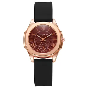 Detail of rose gold quartz watch with red-brown sunray dial and black silicone strap