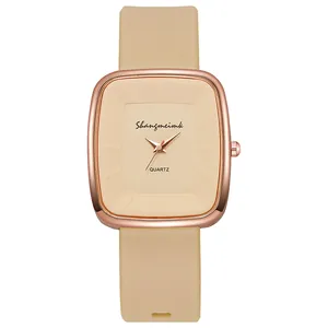 Detail of rose gold square case with beige silicone strap and minimalist dial