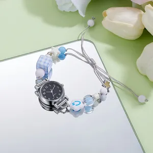 Detail of beaded bracelet quartz watch with blue blocks and charms on a mirror