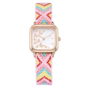 Détail de la montre carrée or rose avec motif papillon et bracelet tissé coloré