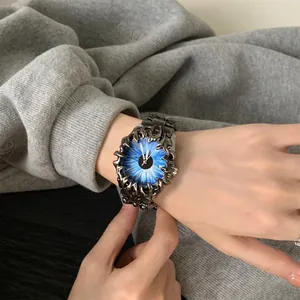 Détail macro de la montre punk avec cadran œil bleu et boîtier griffes métalliques