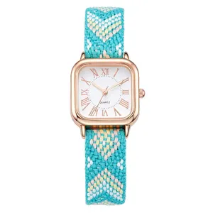 Close-up of vintage square quartz watch with a colorful bohemian woven strap and white dial