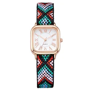 Macro detail of square rose gold watch with colorful ethnic braided fabric strap