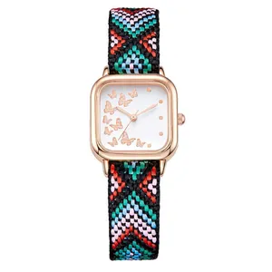 Détail de la montre carrée or rose avec motif papillon et bracelet tissé coloré
