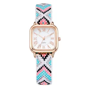 Detail of square rose gold watch with ethnic woven strap and roman numeral dial