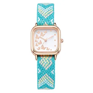 Détail du cadran papillon en or rose avec un bracelet en tissu tissé coloré