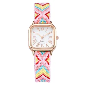 Detail of square rose gold watch with roman numerals and pink woven strap