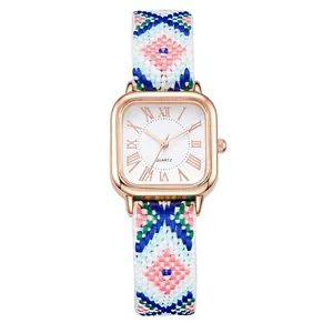 Detail of rose gold square watch dial and colorful woven ethnic style fabric strap