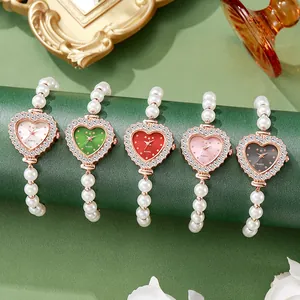 Detalle de cinco relojes con forma de corazón, bisel de pedrería y correas de perlas
