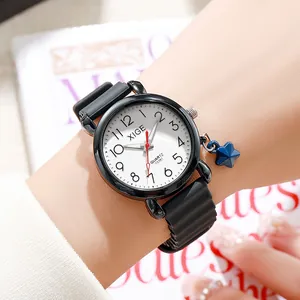 Women's quartz watch with black case, white dial and star pendant on wrist