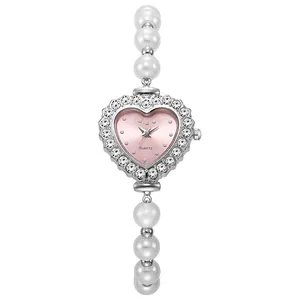 Detalle de un reloj de cuarzo para mujer con forma de corazón y pulsera de perlas blancas