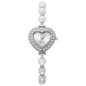 Primer plano de esfera de reloj en forma de corazón con pedrería y perlas blancas