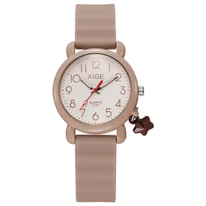 Macro shot of pink silicone quartz watch with rose gold numerals and a star charm