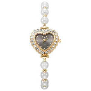 Detalle de reloj con forma de corazón con bisel de diamantes y pulsera de perlas