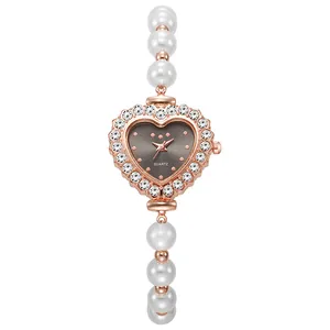 Primer plano de reloj con forma de corazón, bisel de diamantes y pulsera de perlas blancas