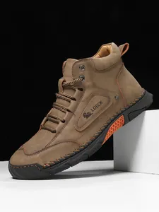 Detail view of brown leather men's boots featuring hand-stitched seams and orange accents
