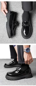 Detail of black patent leather loafers featuring a chunky platform sole and chain buckle