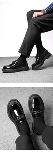 Macro detail of men's black patent leather lug sole loafers with metal chain detail