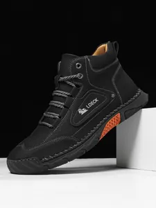 Detail of lychee leather high-top boots with orange accents and reinforced side stitching