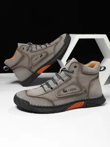 Close-up of retro brown leather men's high-top boots with decorative stitching and orange sole