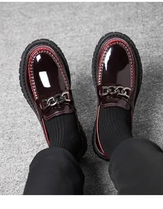Close-up of burgundy patent leather loafer featuring a stylish dark metal chain detail