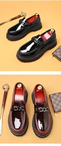 Close-up of black and burgundy patent leather loafers with silver chain and thick sole
