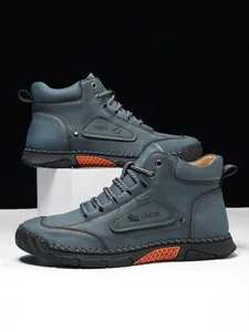 Detail of grey-blue leather boots with stitching, LDECK logo, and orange sole accents
