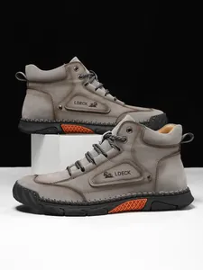 Detail shot of men's leather high-top boots featuring orange mesh sole decor and metal eyelets