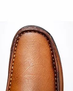 Macro view of brown leather shoe with clear grain texture and durable yellow double stitching