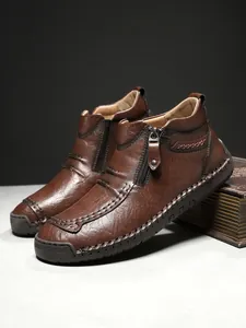 Detail of handmade stitching and side zipper on brown leather casual outdoor boots