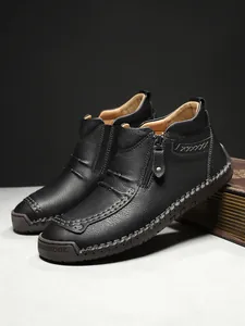 Detail of black leather men's ankle boots featuring hand-stitched seams and a side zipper