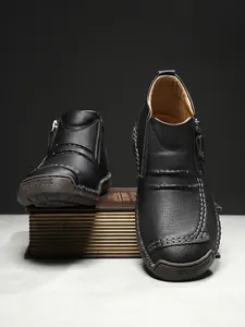 Close-up of black leather boots with manual stitching and side zipper detail