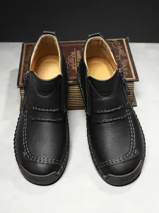 Macro detail of men's leather boots with side zipper, hand stitching and rubber sole