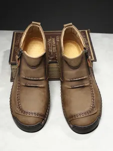 Detail of brown leather boots with manual stitching and side zipper on a retro book