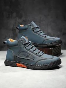 Detail of high-top leather boots with side embossed logo and orange non-slip rubber sole