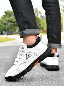 Outdoor-Aufnahme der Herren-Slipper aus weißem Leder mit Gummisohle und orangefarbenen Akzenten