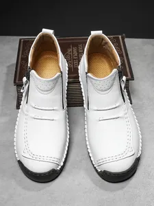 Detailed top view of white leather casual boots with side zippers and side stitching