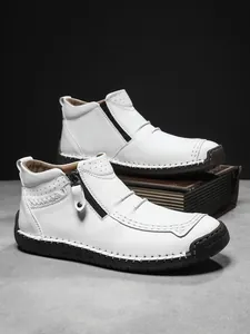 Detail of white litchi grain leather boots with hand-stitched seams and side zipper