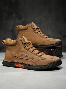 Detailed view of brown men's boots with stitching, brand logo and thick rubber sole