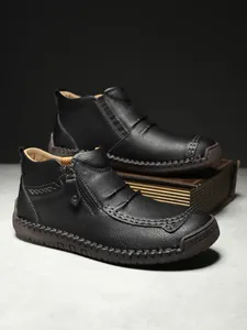 Detail of high-top leather boots featuring hand-stitched seams and side zipper closure