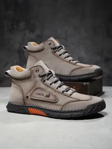 Detail of high-top men's leather boots featuring nubuck texture and orange sole accents