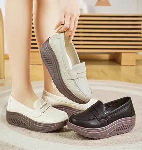 Dettaglio di mocassini con zeppa comodi con suola spessa in finta pelle nera e beige