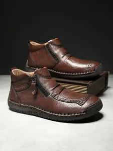 Detailed close-up of brown leather ankle boots with hand-stitched seams and zipper closure