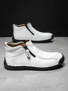 Macro detail of men's white leather boots featuring side zipper and reinforced hand stitching