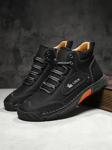 Detailed close-up of men's black lychee grain leather boots with orange sole accent