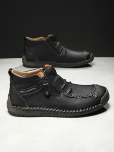 Detail of premium lychee texture leather upper and side zipper on men's black boots