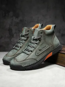 Detail of grey nubuck leather boots featuring orange mesh accents and embossed logo