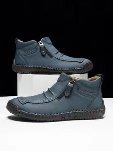 Detail view of men's leather high-top boots with side zipper and reinforced cross stitching